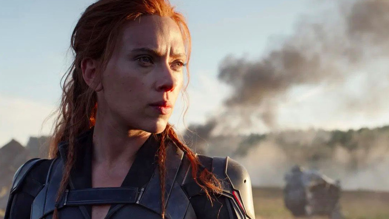Scarlett Johansson as Natasha Romanoff in a scene with a solemn expression, explosions in background