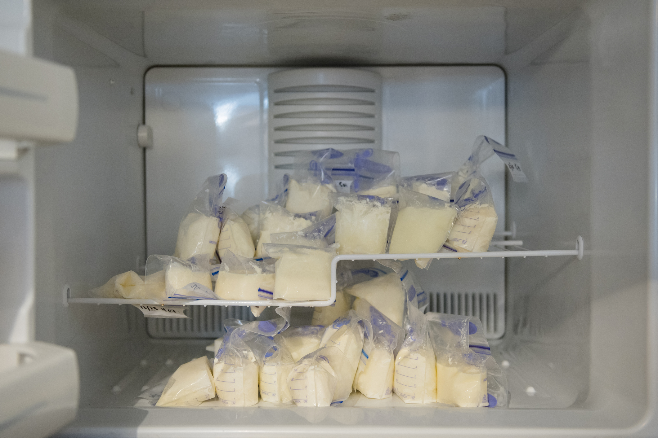 Breast milk stored in labeled bags inside a refrigerator freezer