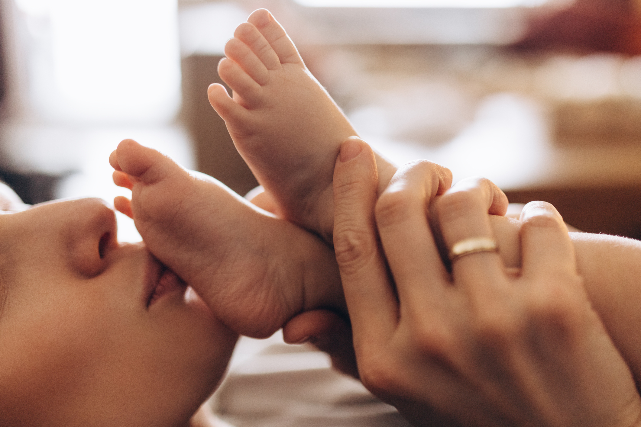 Adult gently holding a baby&#x27;s foot close to their face, expressing affection