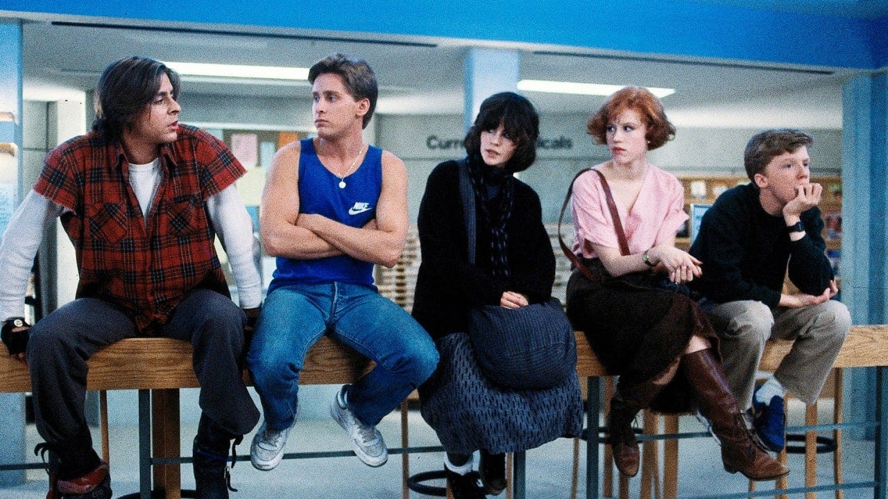 Five characters from &quot;The Breakfast Club&quot; movie seated in a row, each showcasing distinct styles of &#x27;80s attire