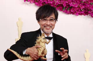 Takashi Yamazaki posing with a Godzilla toy on the Oscars red carpet