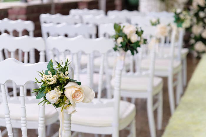 chairs set up for a wedding ceremony with floral decorations attached to the end chairs