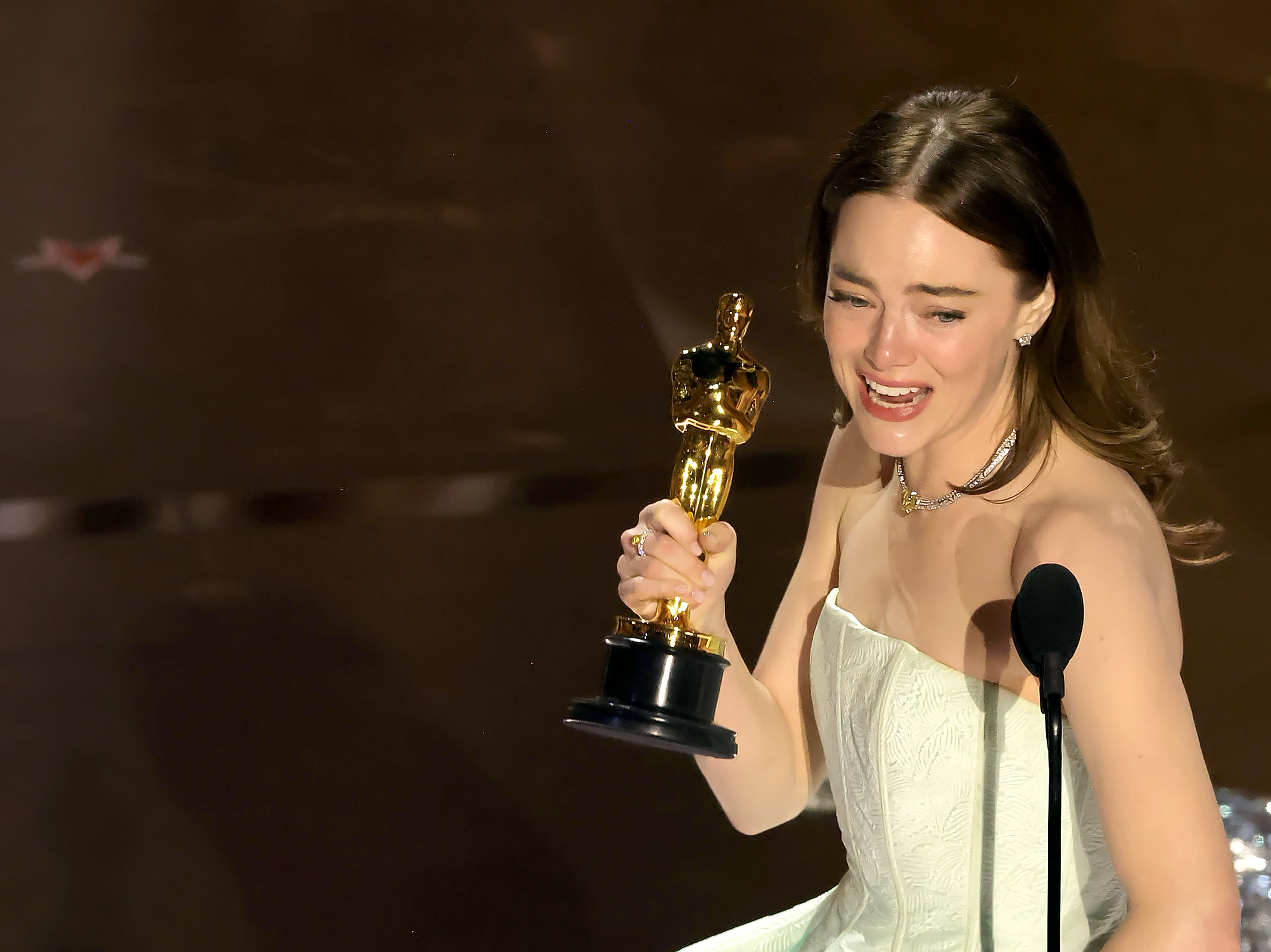 Emma Stone holding her Oscar onstage