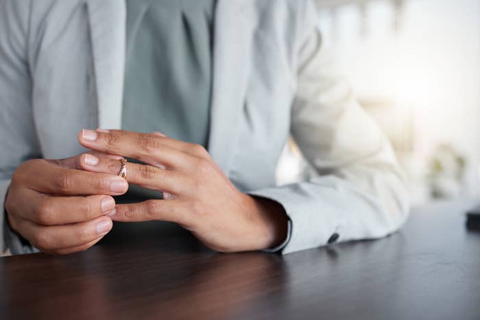 Person at table with hands taking off a wedding ring