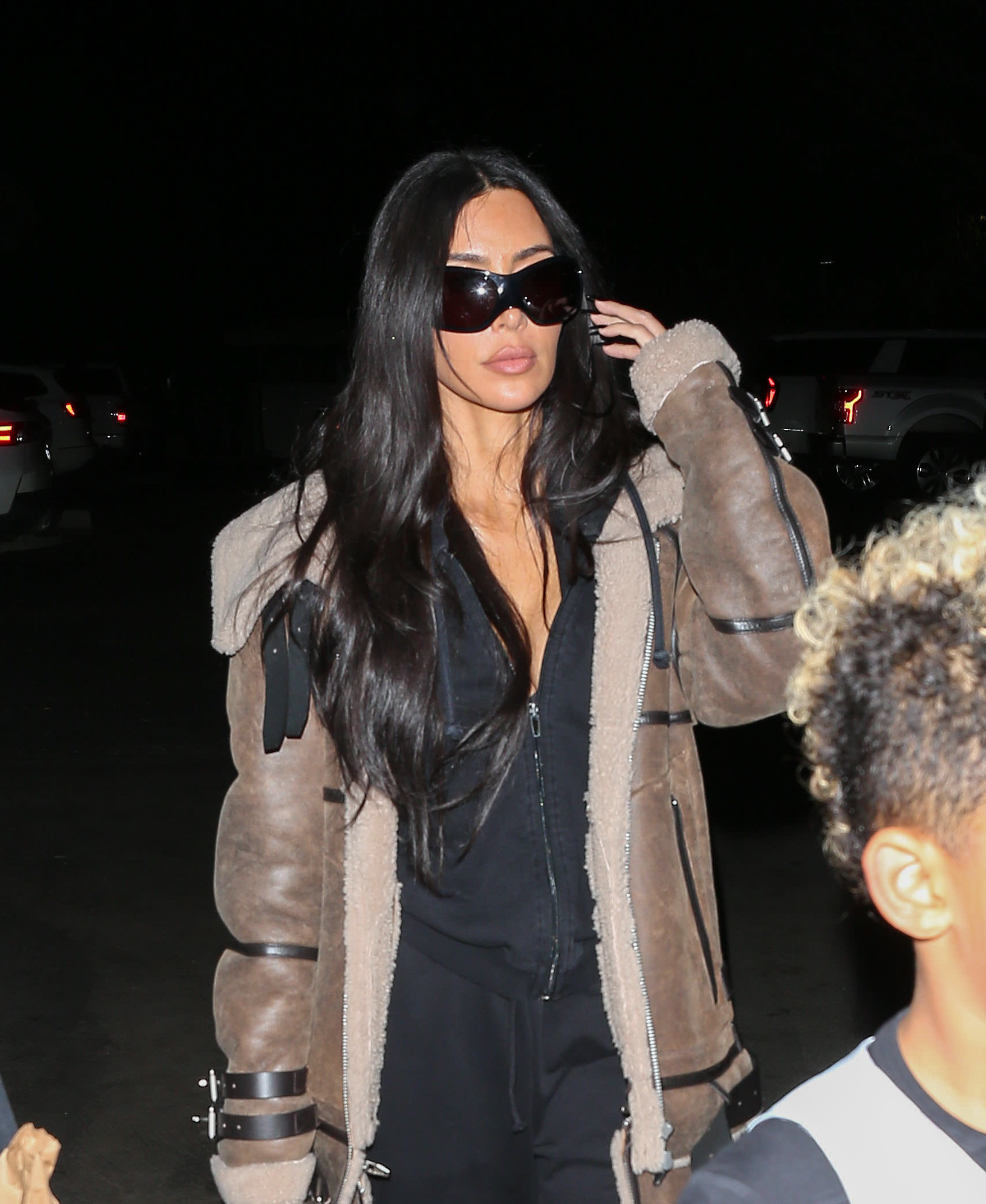 Closeup of Kim Kardashian walking outside at night with sunglasses on