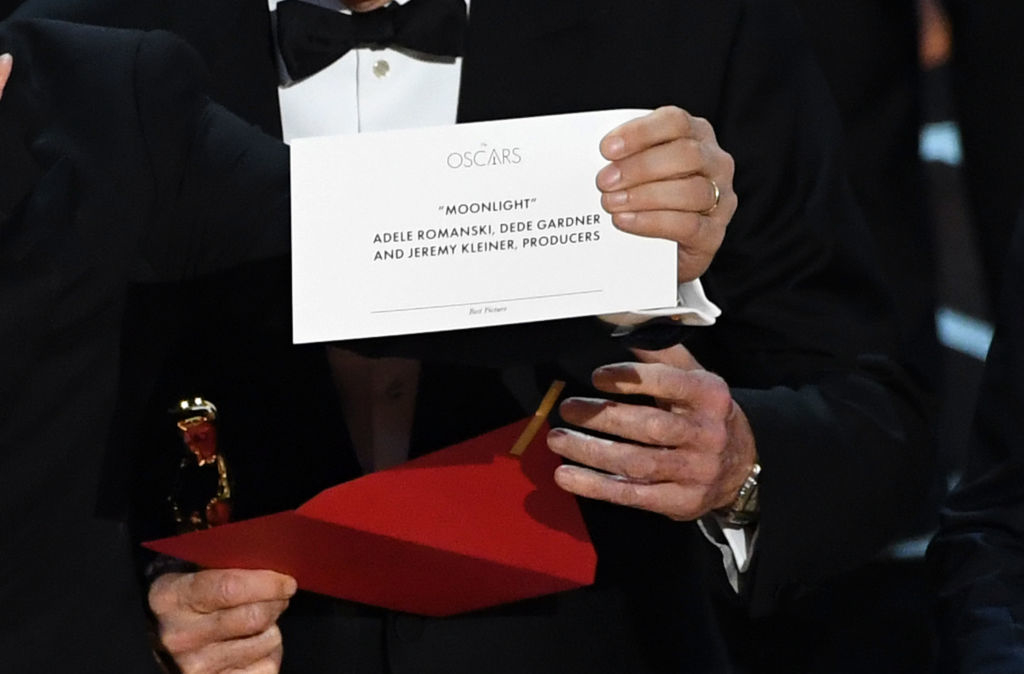 Person holding an envelope and Oscar award with a card stating &quot;MOONLIGHT&quot; as Best Picture, names Adele Romanski, Dede Gardner, Jeremy Kleiner as producers