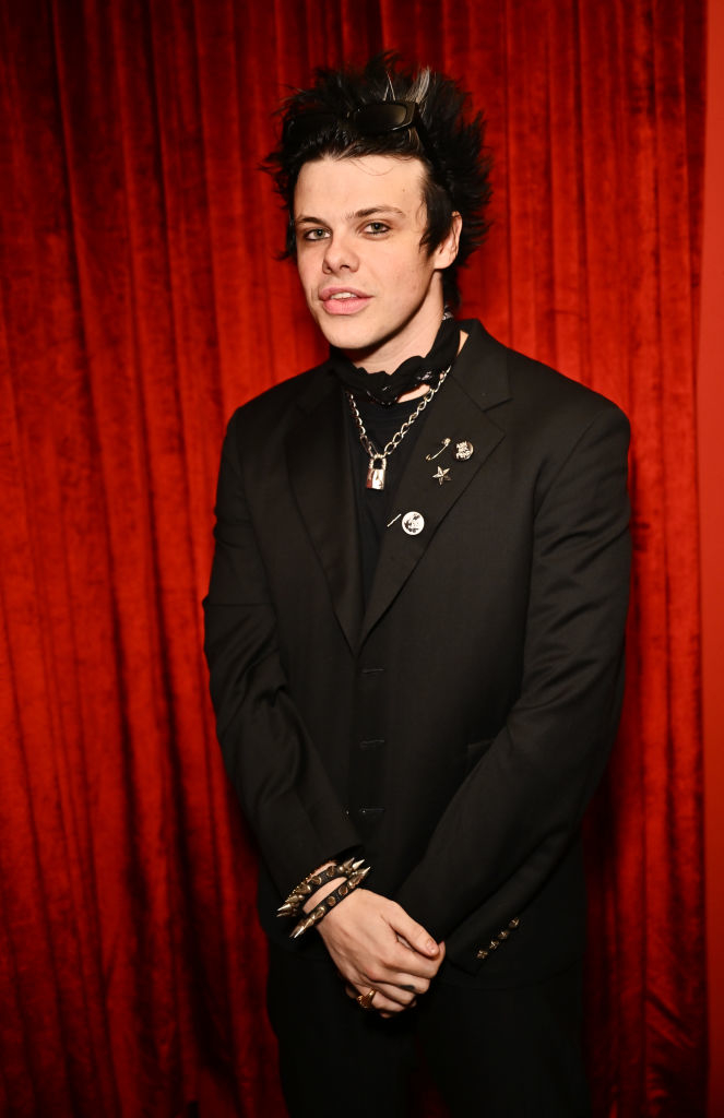 Yungblud in suit with spiked hair and layered necklaces at an event