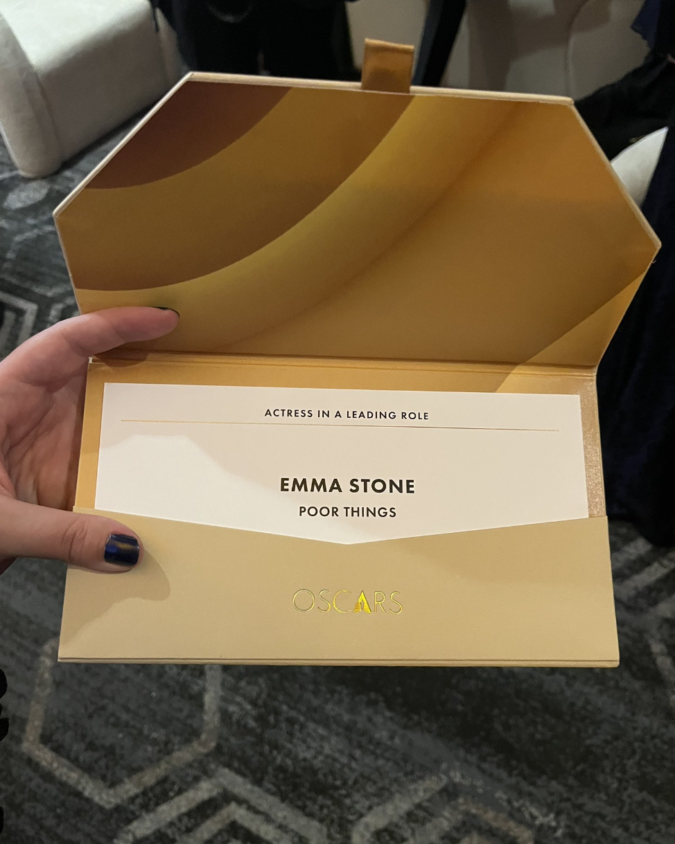 Hand holding an envelope labeled &quot;ACTRESS IN A LEADING ROLE&quot; with &quot;EMMA STONE&quot; and &quot;OSCARS&quot; written inside
