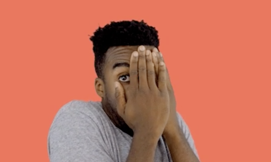 Man covers half of his face with his hand, looking surprised