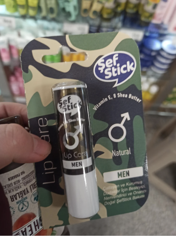 Hand holding a camouflage package of &#x27;Sef Stick Lip Care for Men&#x27; with a lip balm tube visible