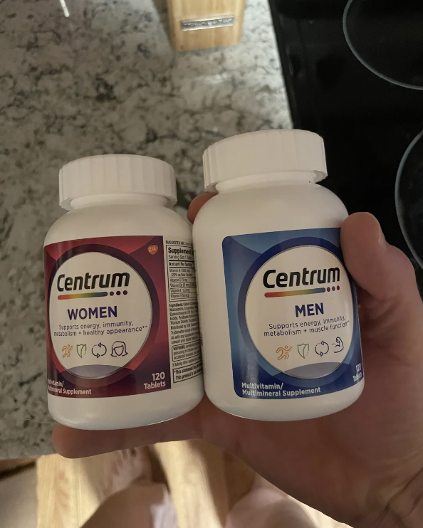 Two bottles of Centrum multivitamins, one for women and one for men, being held