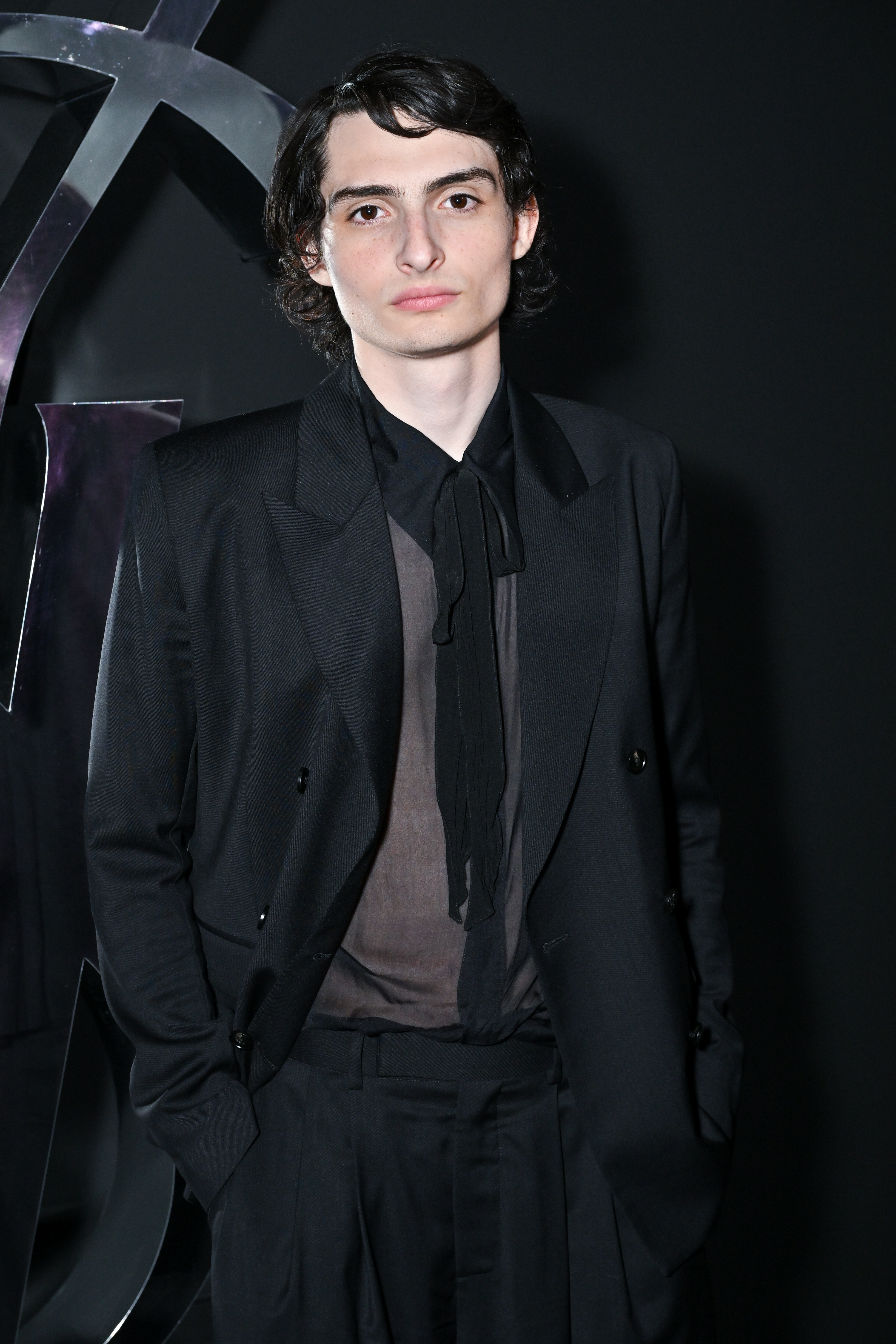 Person in a black suit with tie poses at a movie event