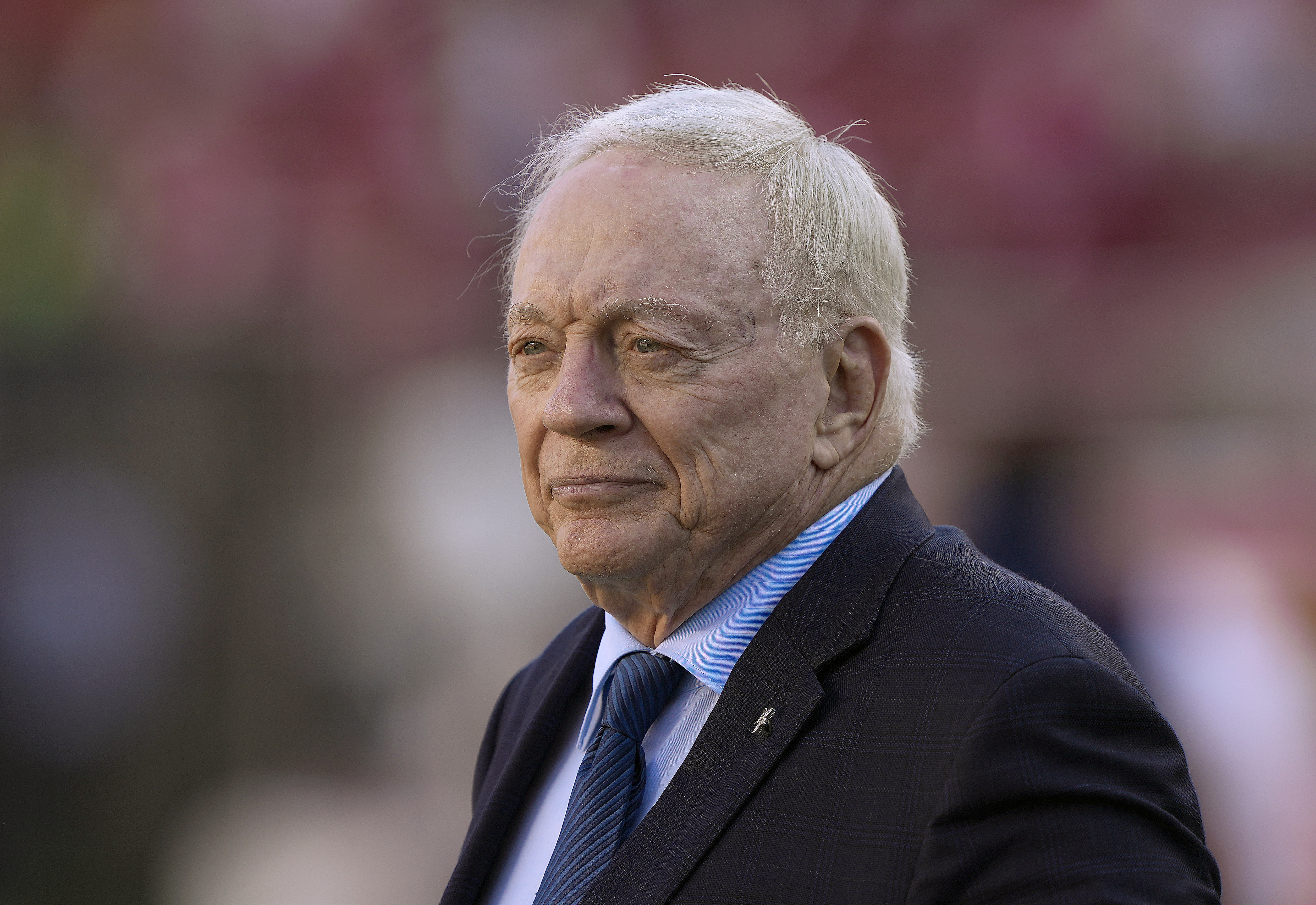 Elderly man with a content expression wearing a suit and tie at a sports event