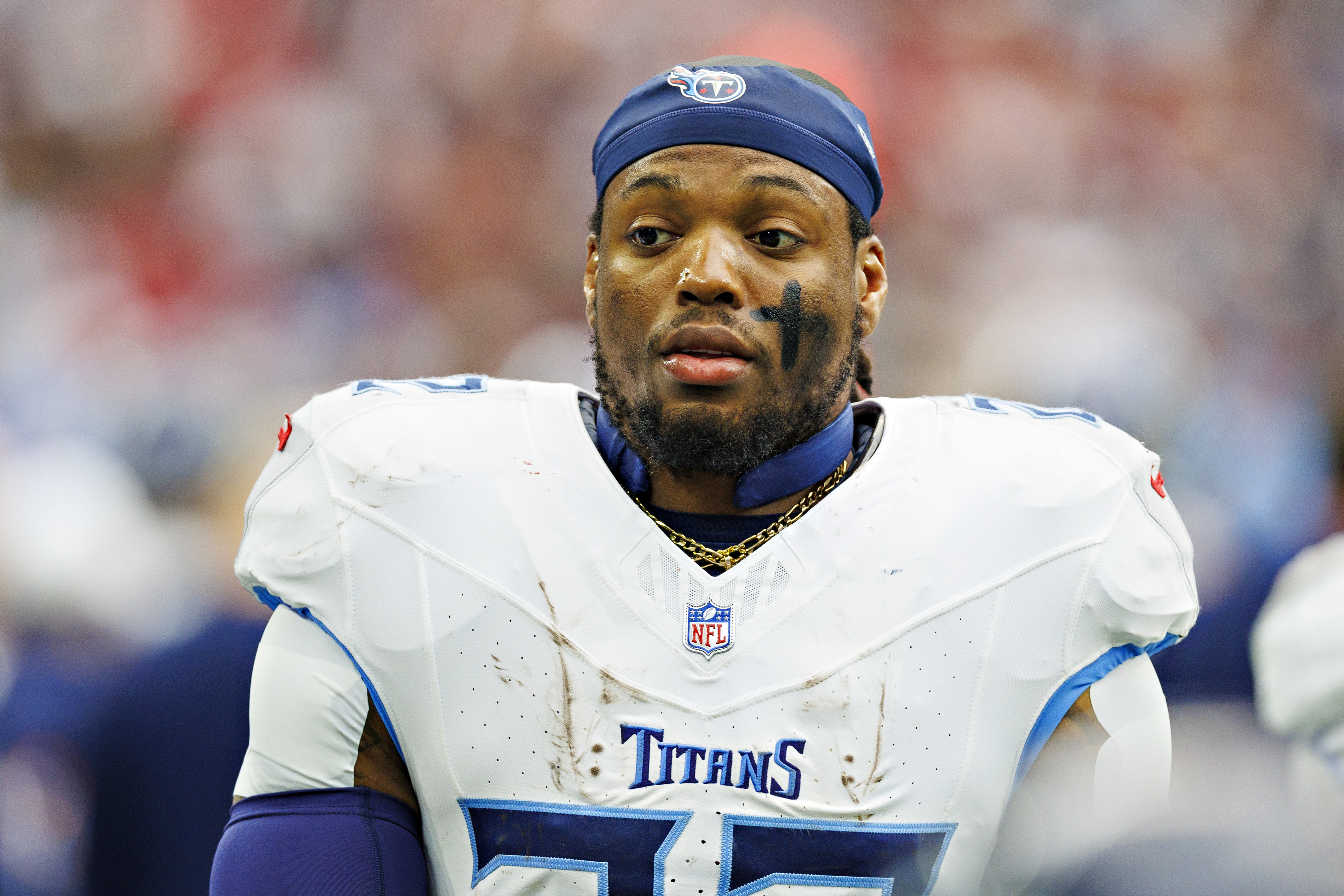 NFL player in Titans uniform, focused look, helmet with visor off-head, on field