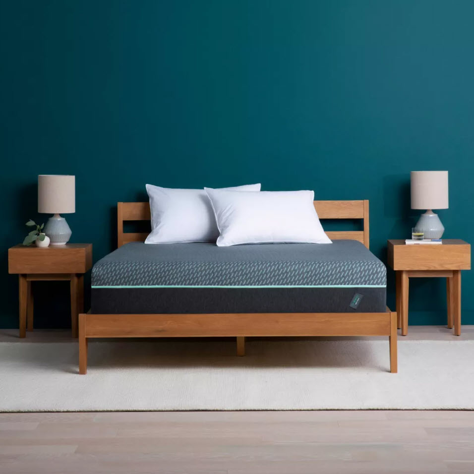 A modern bed with white pillows, flanked by two nightstands with lamps, against a teal wall