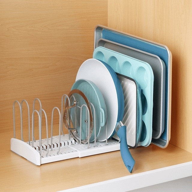 Expandable rack holding plates and cookware in an organized kitchen cupboard