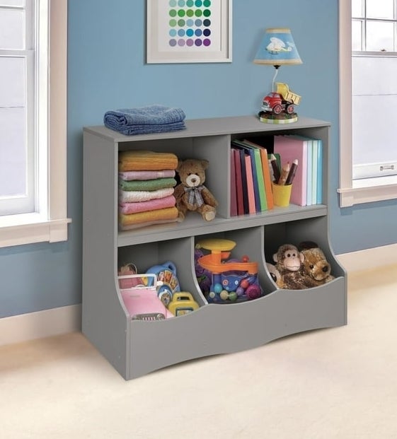 Gray children&#x27;s storage unit with shelves and toy bins in a room
