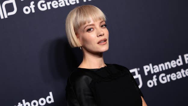 Lily Allen in black outfit on event backdrop, looking at camera, short hair styled