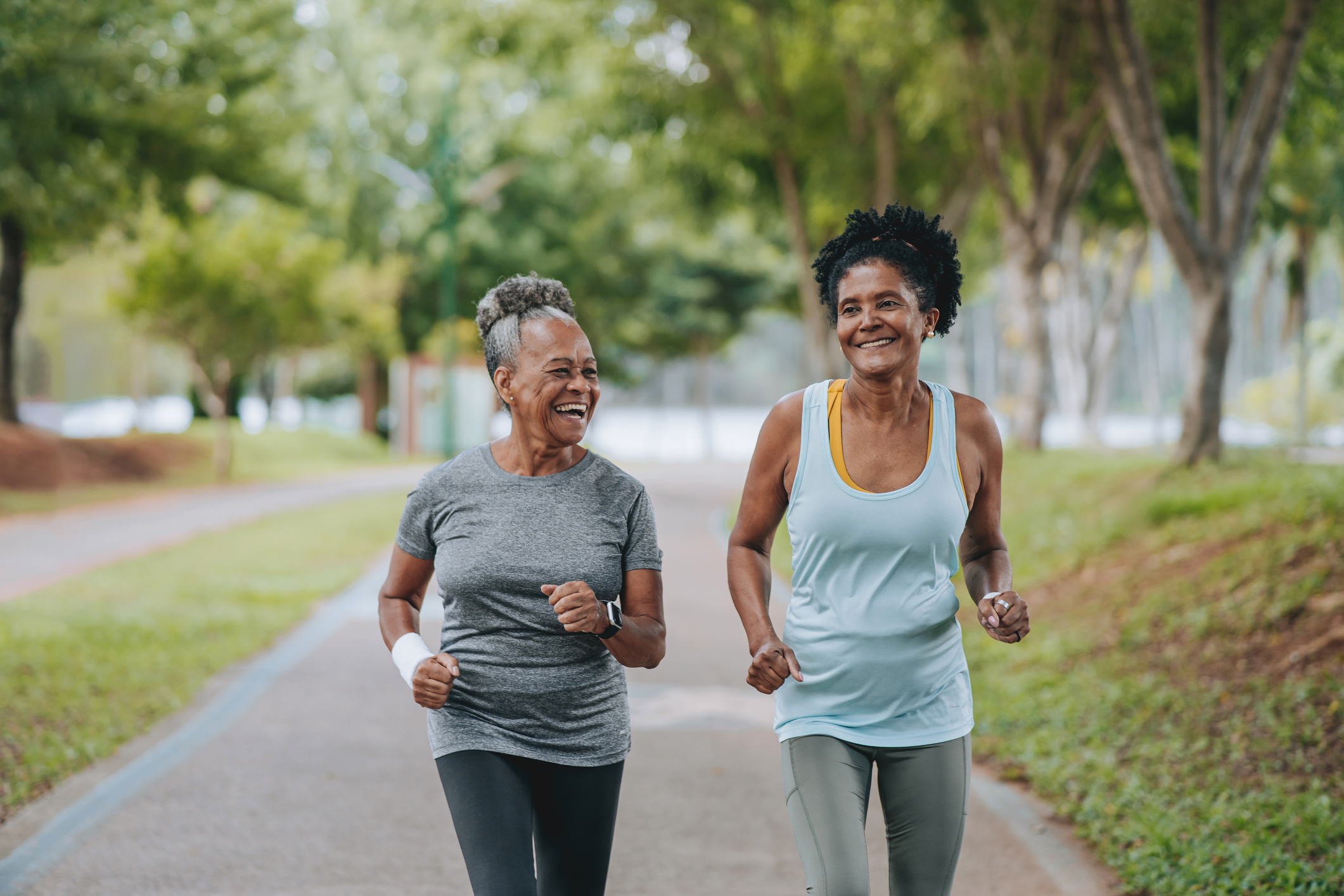 Two older women jogging together in a park