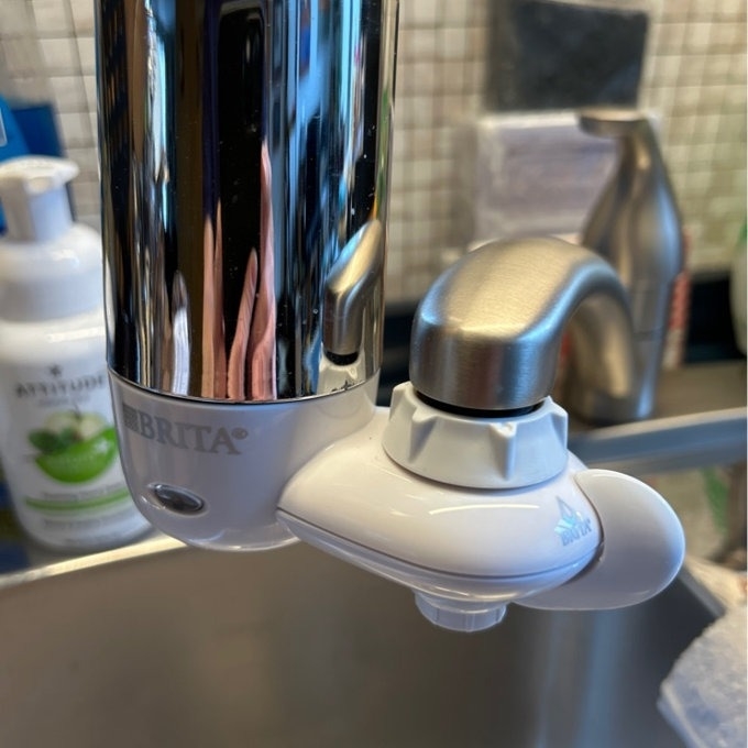 A Brita water filter attached to a kitchen faucet for clean drinking water
