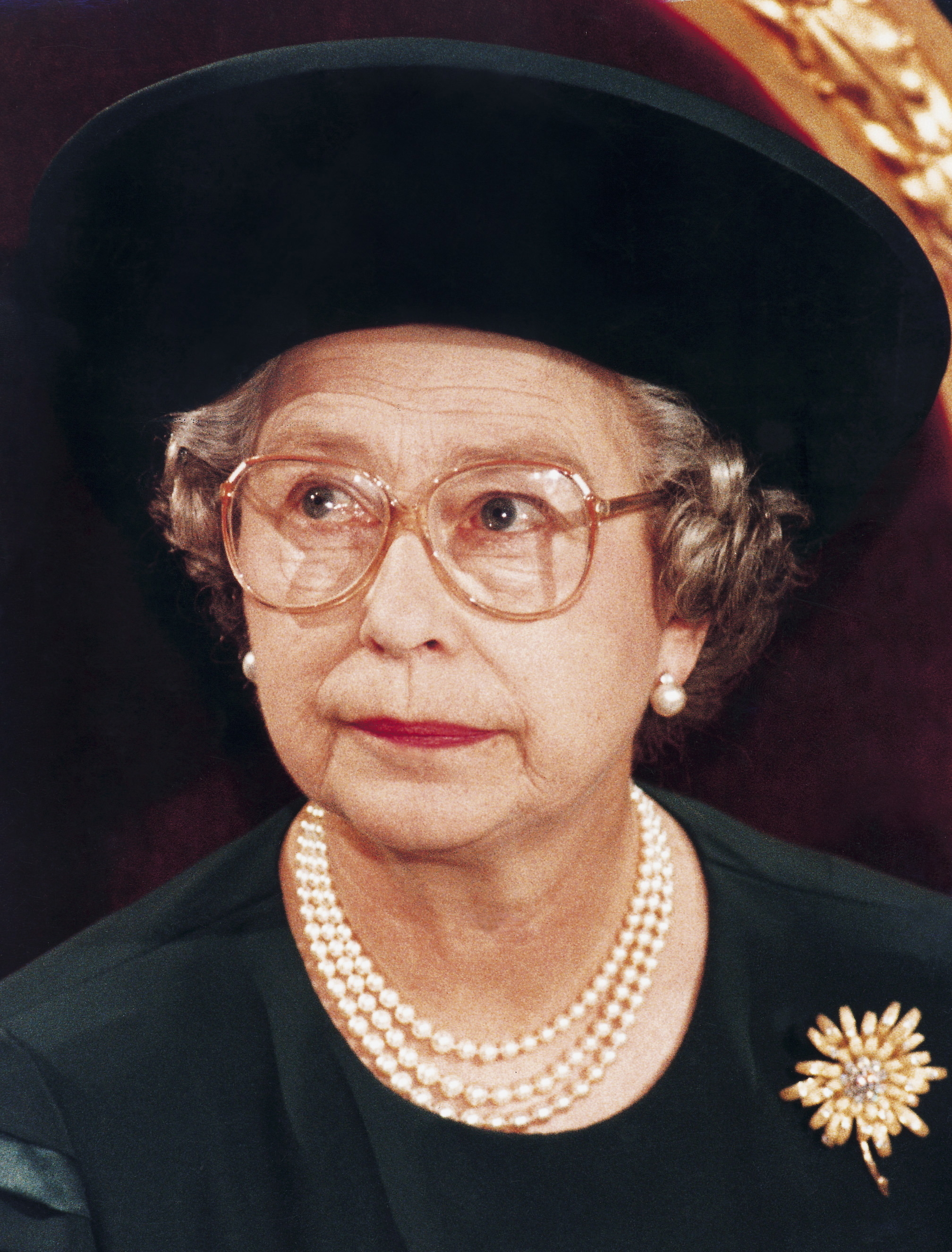Queen Elizabeth II wearing pearls and a decorative brooch