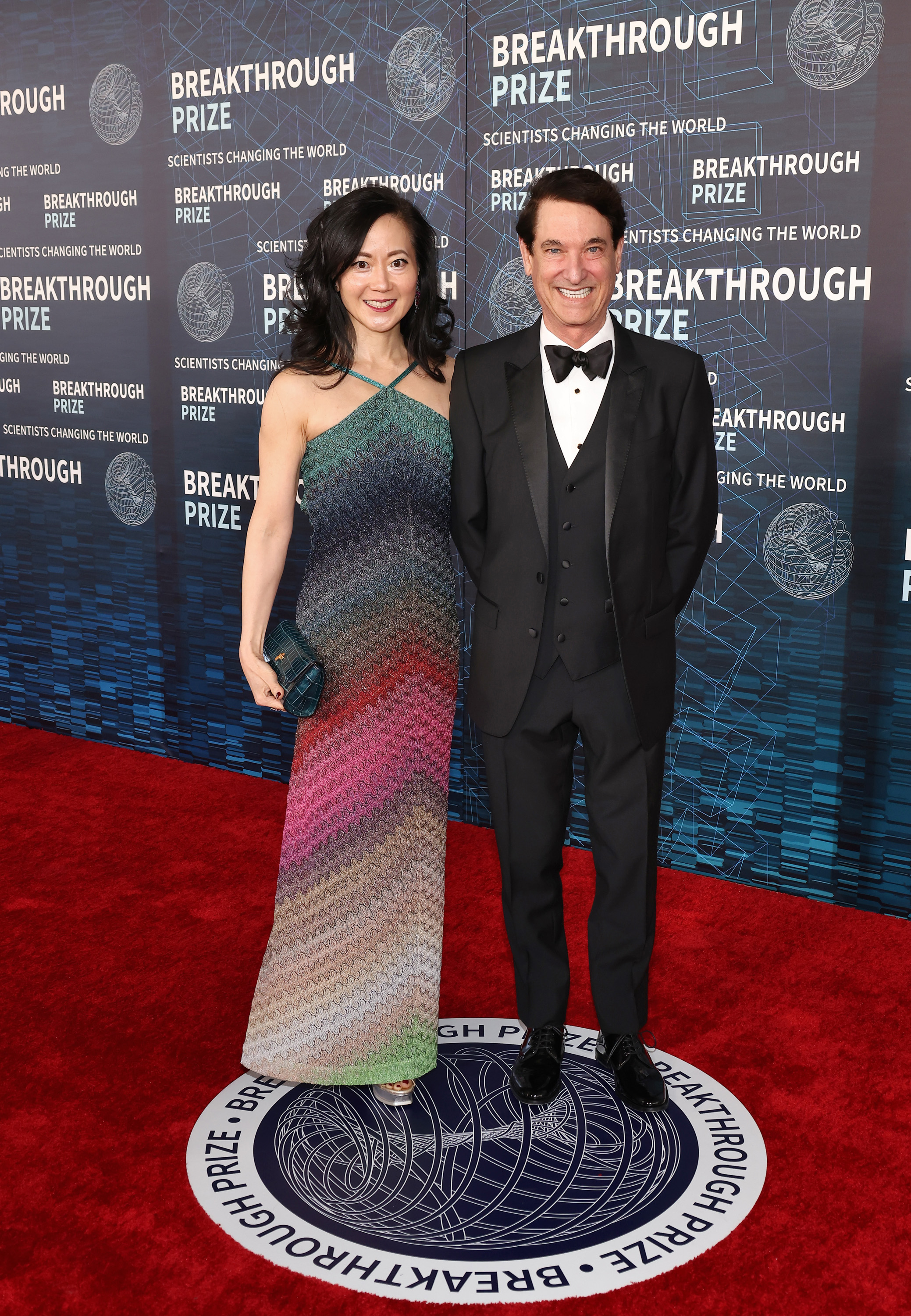 Two people on the red carpet, woman in a gradient dress and man in a black suit at the Breakthrough Prize event