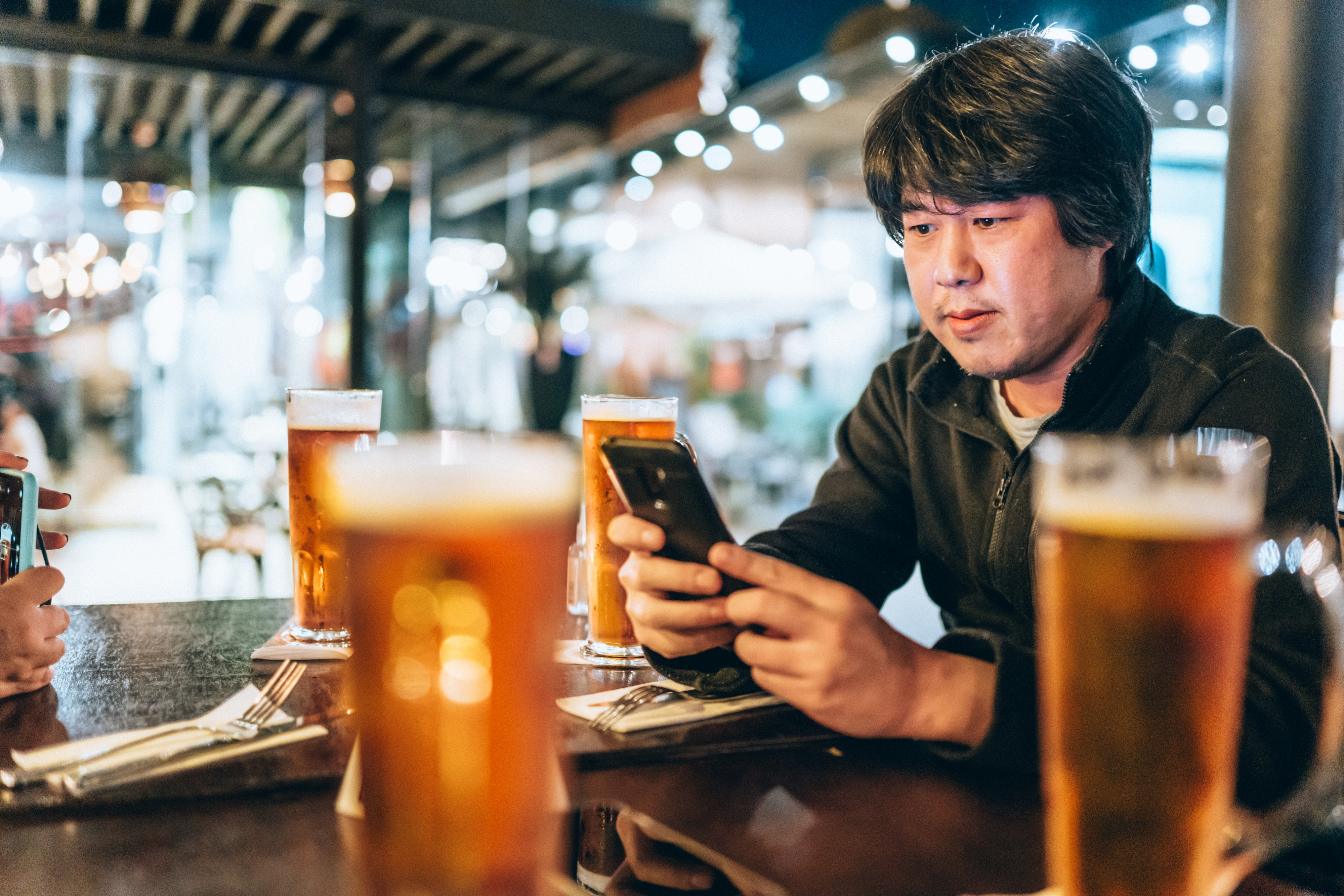 Man sitting at a table with beers, using a smartphone