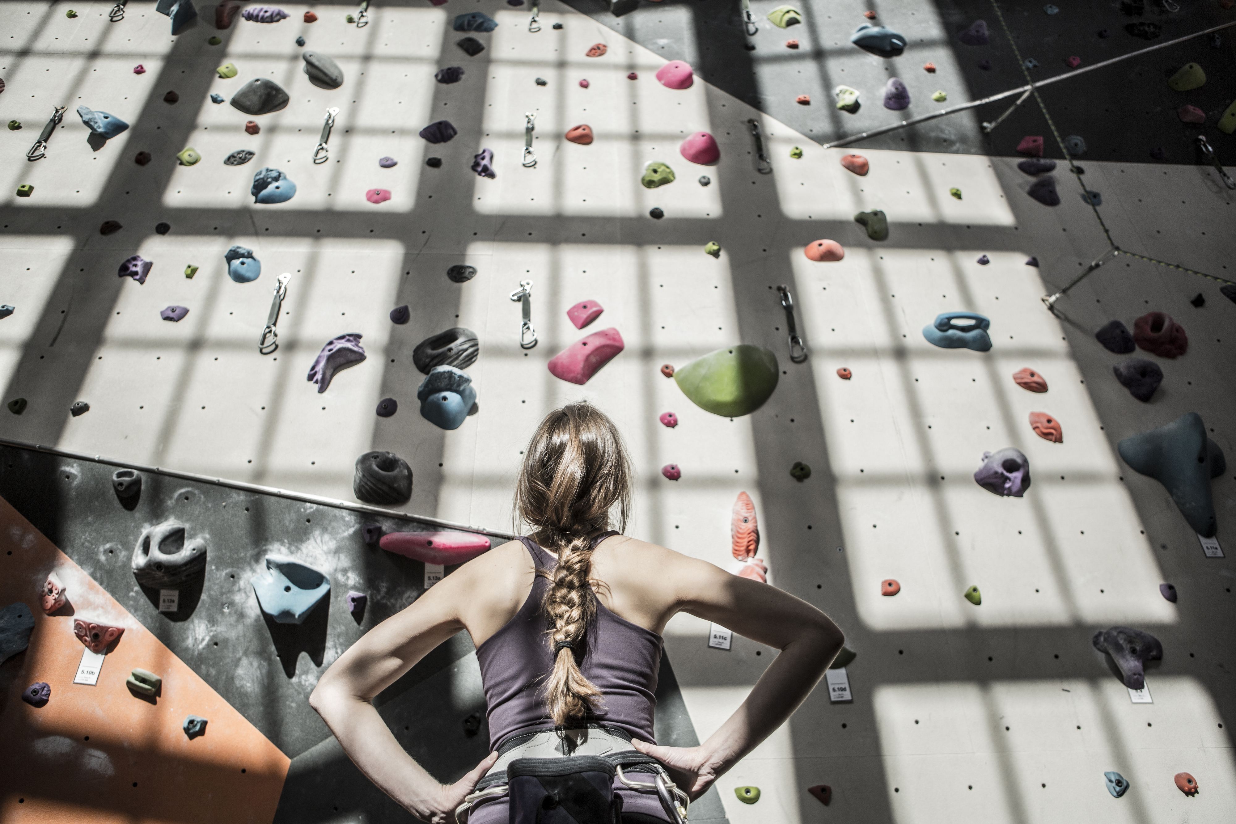 Woman in sportswear preparing to climb an indoor rock wall with various handholds