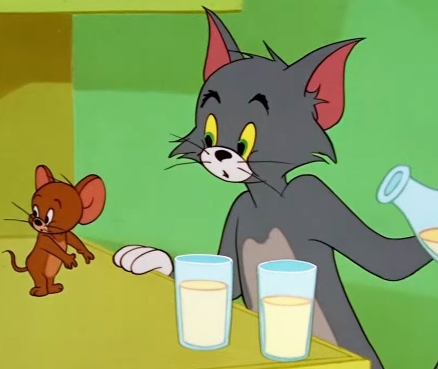 Tom the cat pours milk for Jerry the mouse in a classic cartoon scene