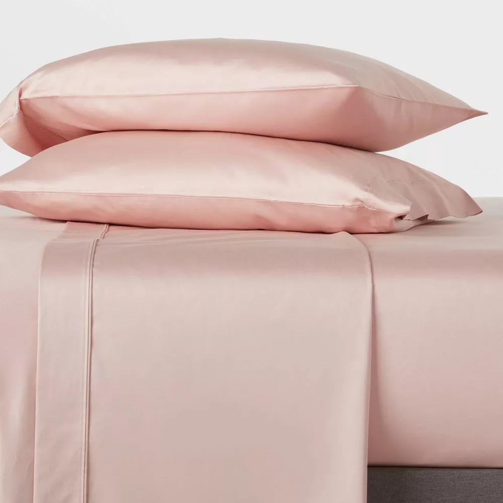 the pink sheets on a bed and two pillows