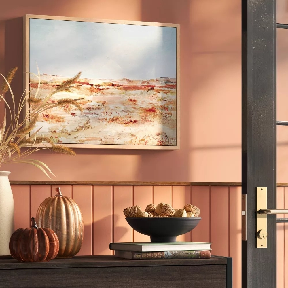 Painting of a serene landscape on a wall above a modern side table with decorative items