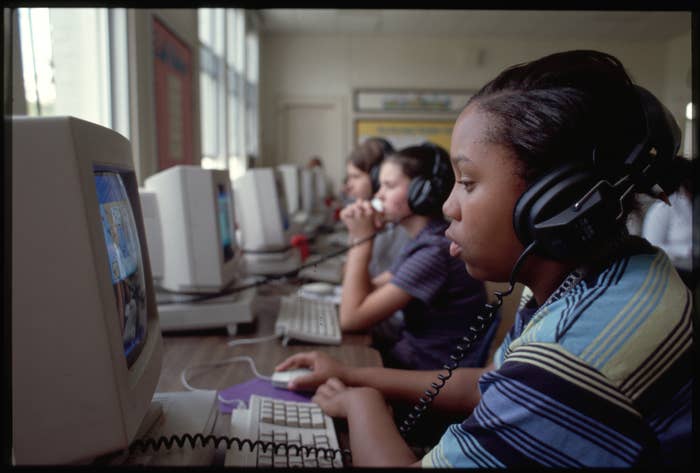 Three students wearing headphones using computers in a classroom setting