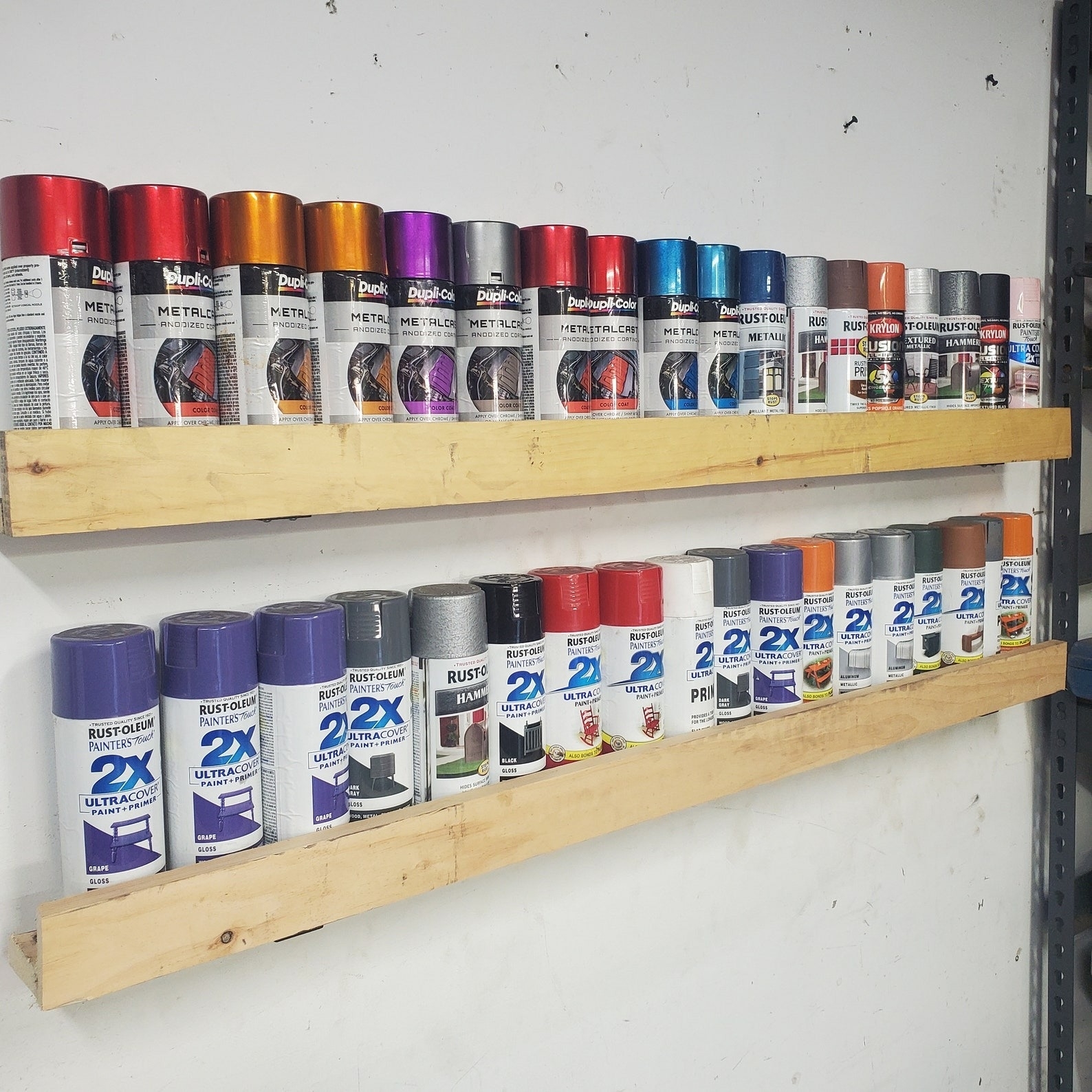 Shelves displaying a variety of spray paint cans in different finishes and brands