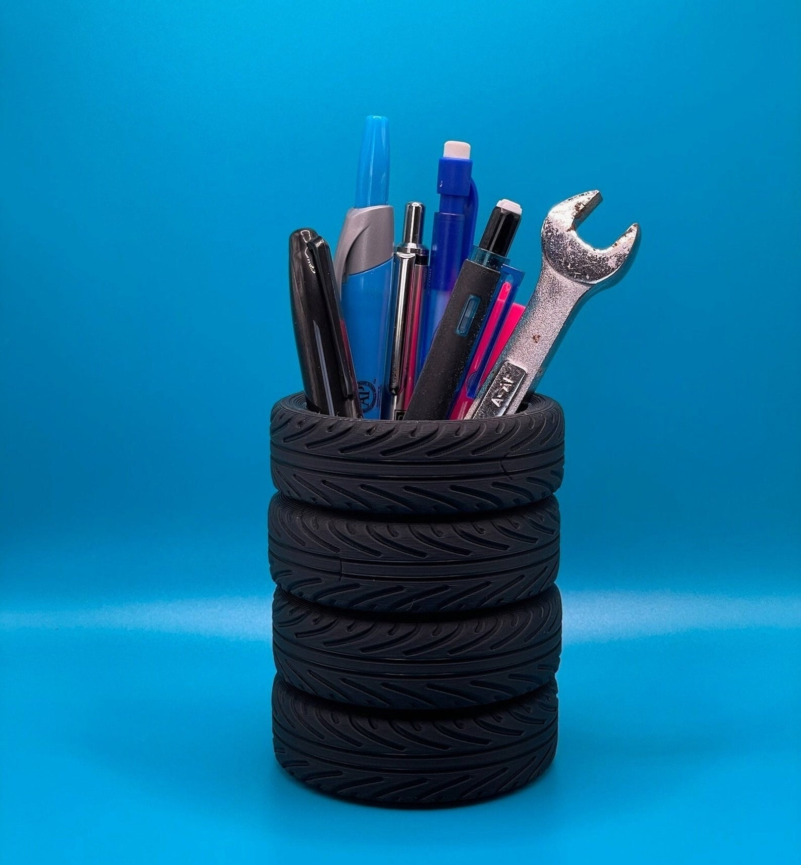 A pen holder made from recycled materials with pens and a wrench inside, demonstrating eco-friendly desk organization options