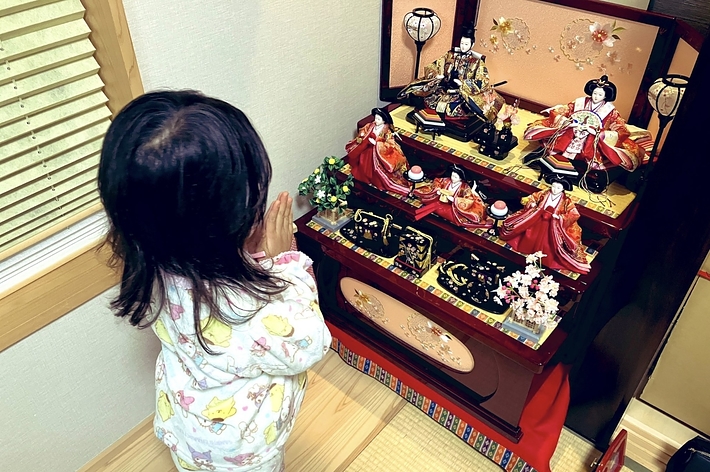 子供がひな祭りの雛人形を見ている。