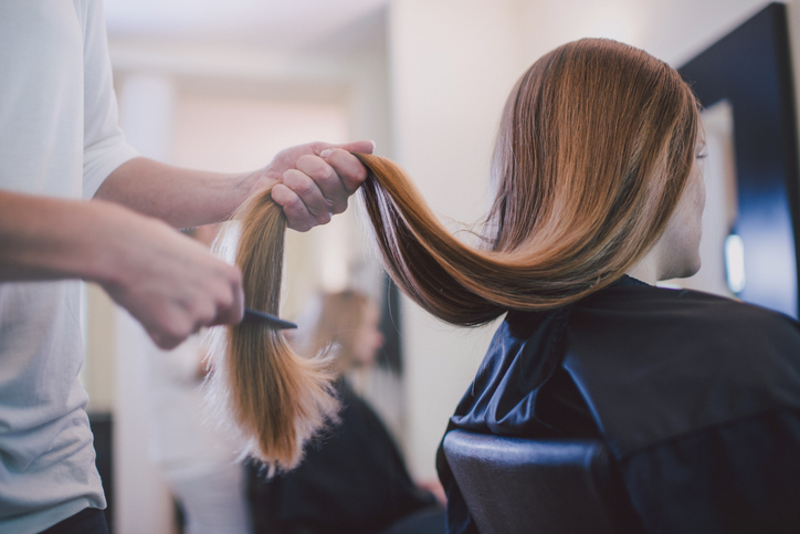 Hairdresser trimming the ends of a client&#x27;s straight hair in a salon