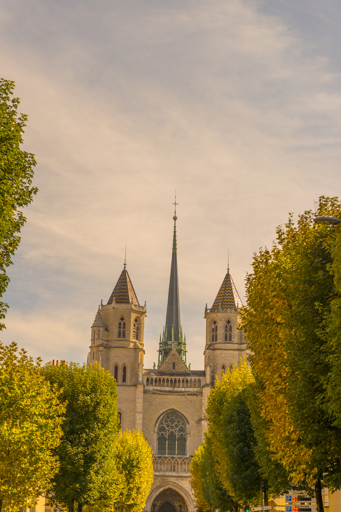 Gothic cathedral with spire between trees under a sunset sky