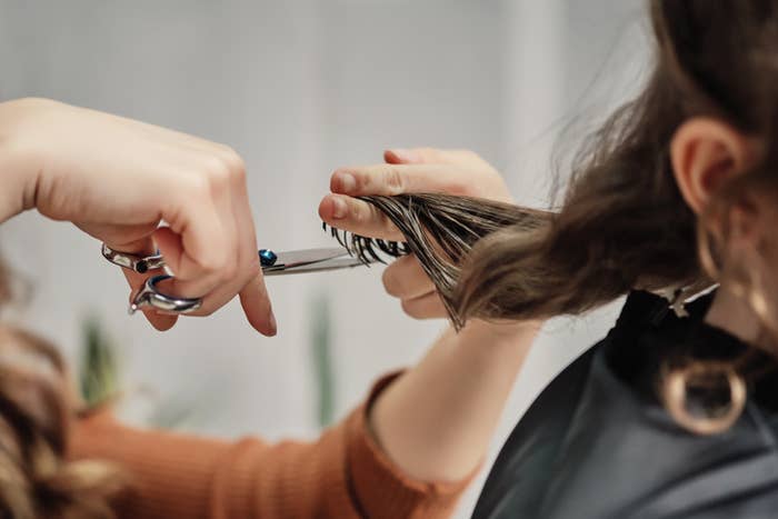 Hairdresser cutting a person&#x27;s hair, focus on hands and scissors