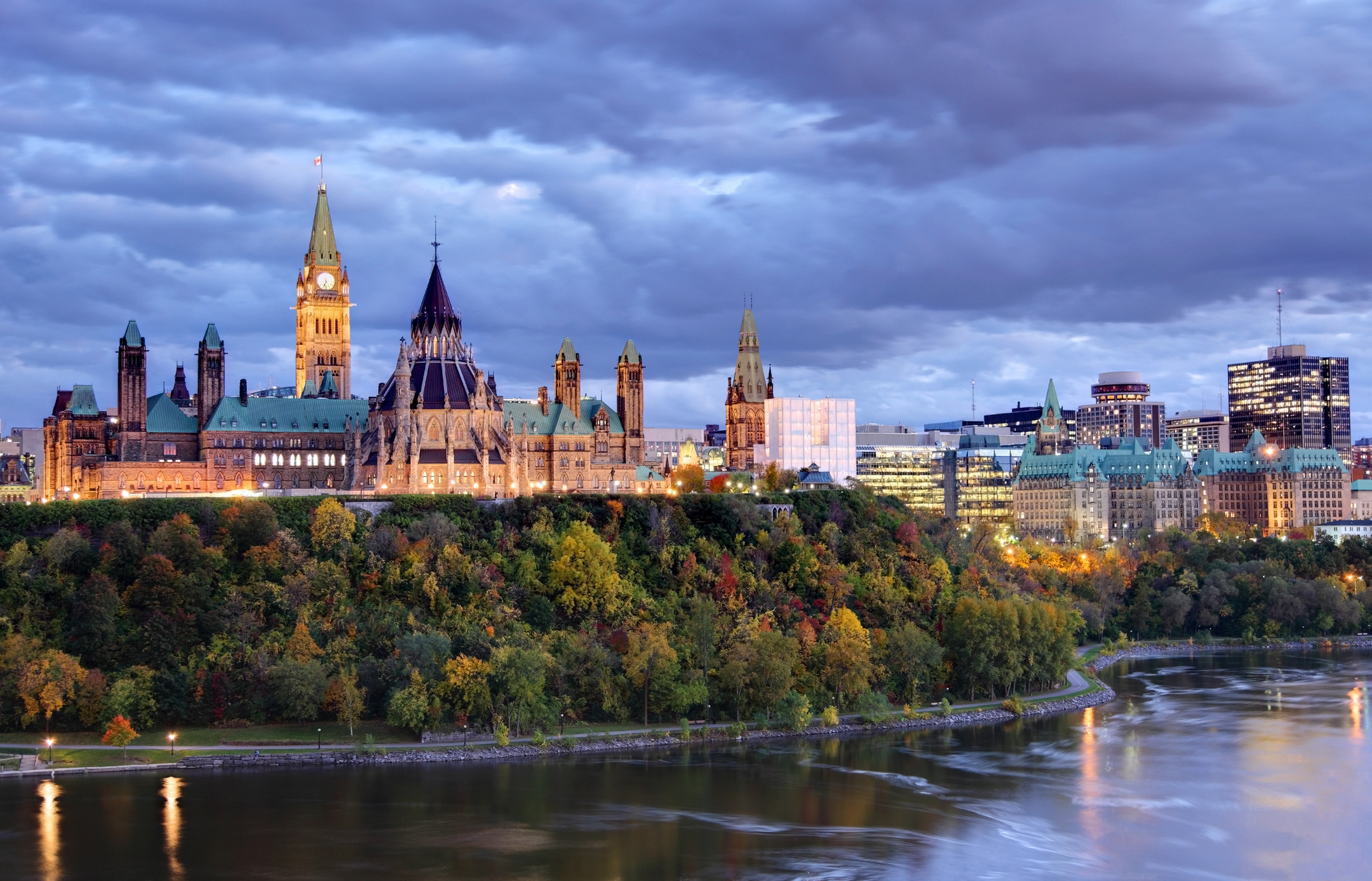 Ottawa&#x27;s Parliament Hill beside a river at dusk with clouds in the sky