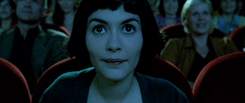 Woman smiling with short hair, sitting in a theater, from movie &quot;Amélie.&quot;