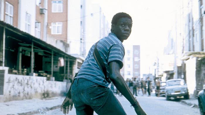 Young man in a striped shirt looks back while walking on a city street