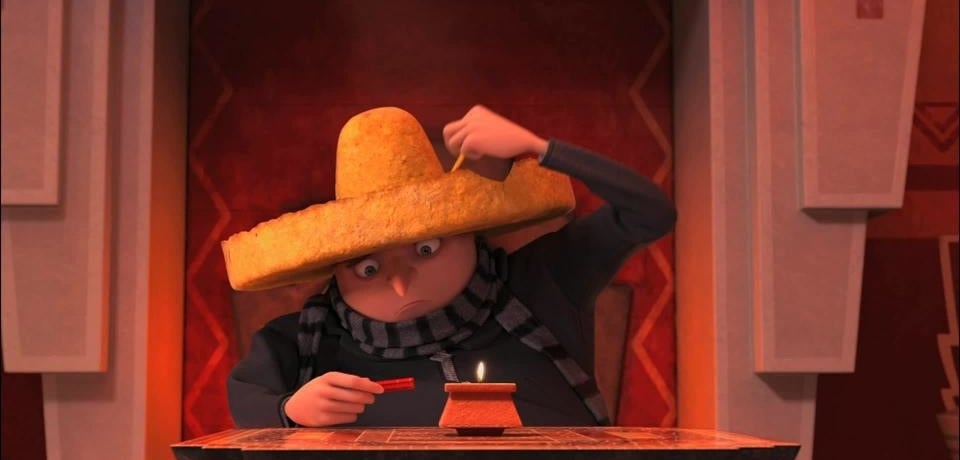 Animated character Gru from Despicable Me in a large sombrero, sitting with a mischievous expression
