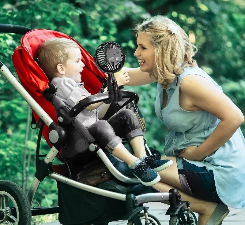 model smiling at child in stroller with a clip-on fan attached