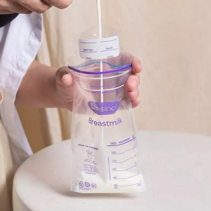 Hand pouring liquid into a labeled breast milk storage bag