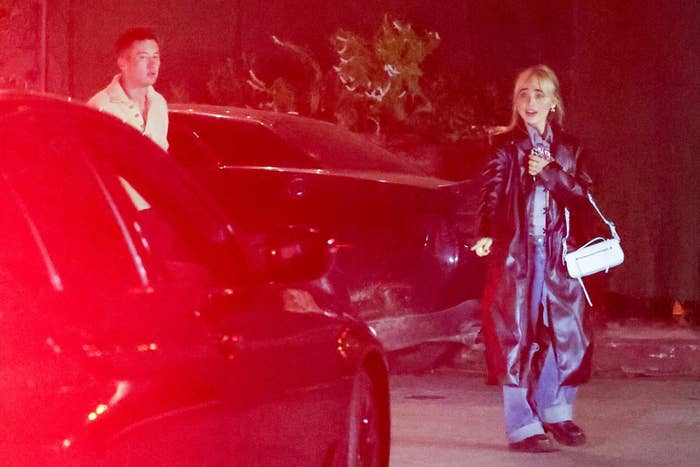 Sabrina Carpenter in a long coat and jeans, with Barry a few steps behind her