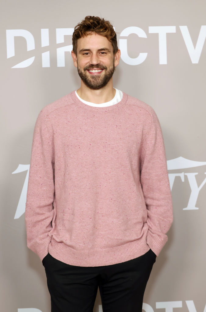 Nick in sweater and trousers posing with hands in pockets at event