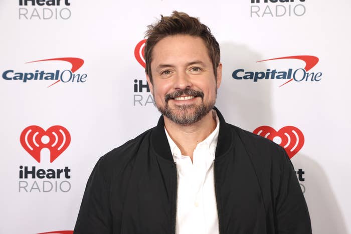 Will Friedle wearing a light jacket over a dress shirt, at the iHeartRadio event