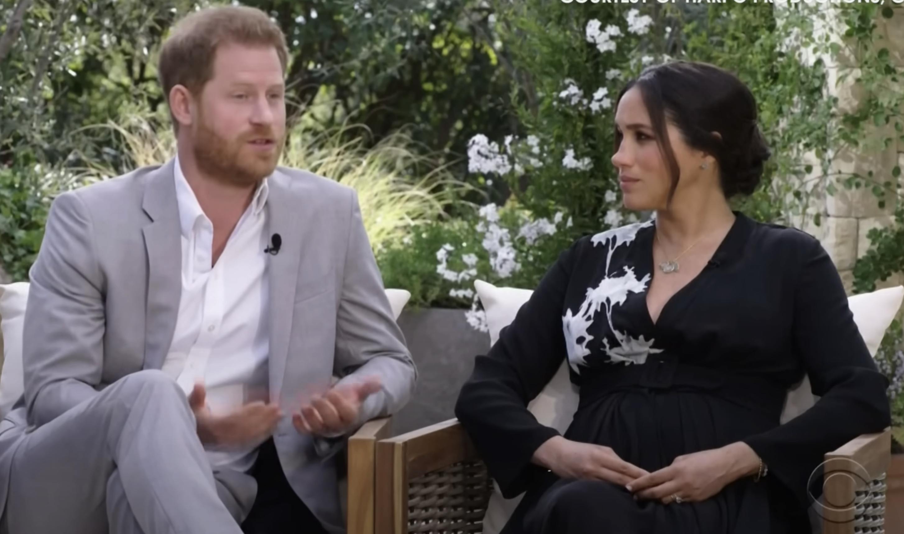 Prince Harry and Meghan Markle seated during an interview with Oprah, Meghan in a black dress with white patterns