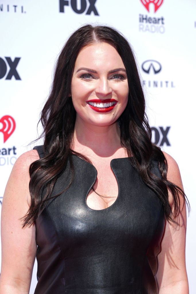 Danielle smiling, wearing a sleeveless leather dress at a media event