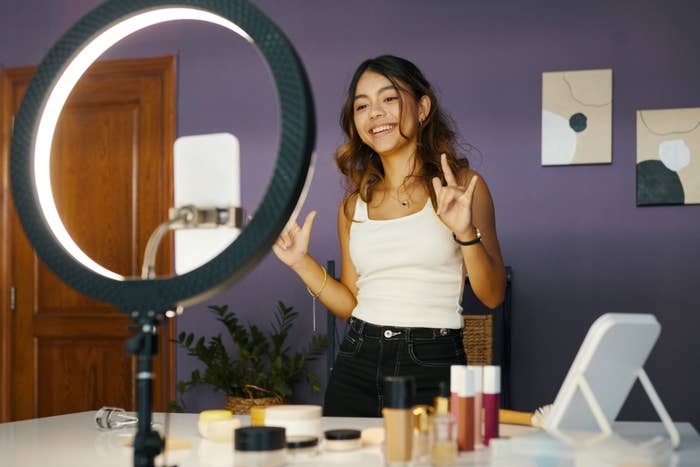 Young person filming a makeup tutorial with a ring light